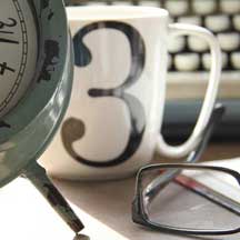 A Clock, Cup of Coffee, Glasses and a Keyboard